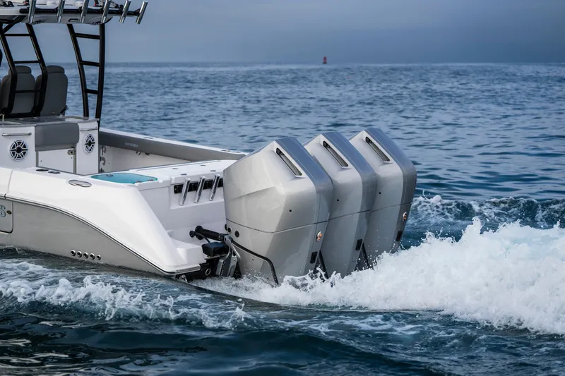 Slide: The Image of 2024 Everglades 365 Center Console boat with triple engines cruising on open water. - 48