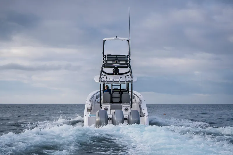 Slide: The Image of 2024 Everglades 365 Center Console boat cruising on open water under cloudy skies. - 51