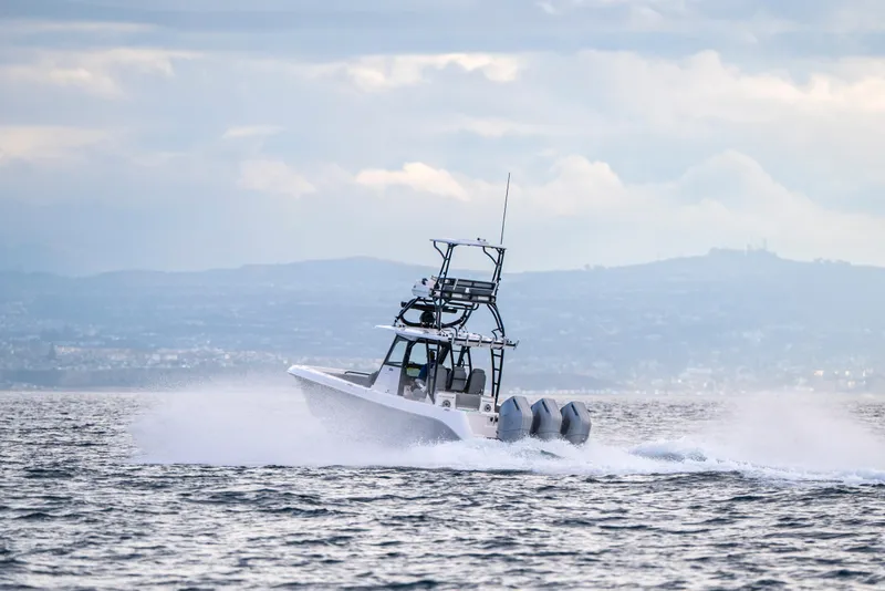 Slide: The Image of 2024 Everglades 365 Center Console boat cruising on open water, scenic backdrop. - 67