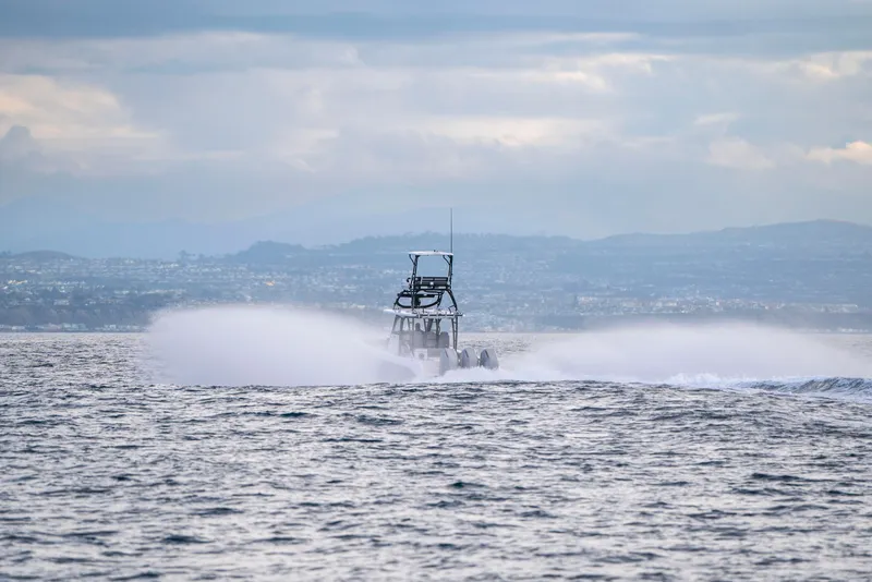Slide: The Image of 2024 Everglades 365 Center Console speeding on open water with scenic coastal backdrop. - 68