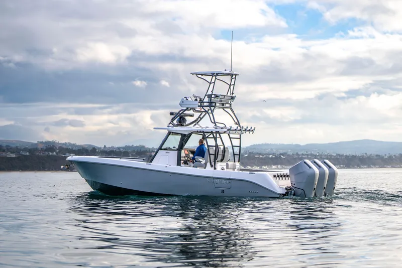 Slide: The Image of 2024 Everglades 365 Center Console boat cruising on calm waters under a cloudy sky. - 70