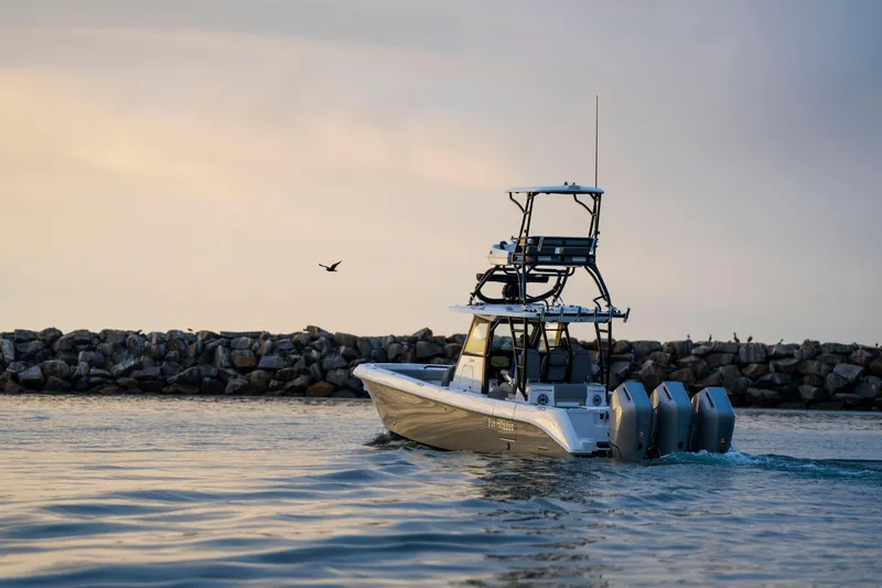 Slide: The Image of 2024 Everglades 365 Center Console boat cruising near rocky shoreline at sunset. - 8