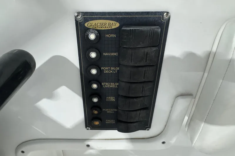 Slide: The Image of Control panel of 2003 Glacier Bay 2640SX Renegade catamaran with labeled switches. - 19