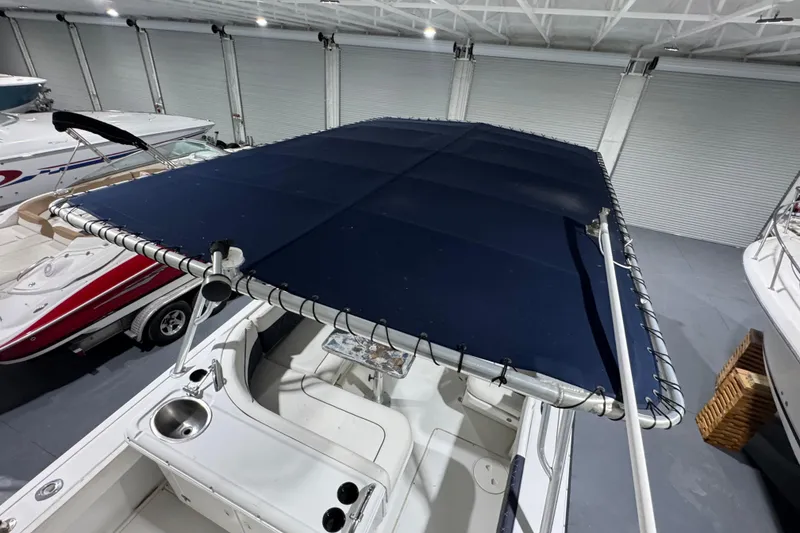 Slide: The Image of 2003 Glacier Bay 2640SX Renegade boat with blue canopy in indoor storage. - 27