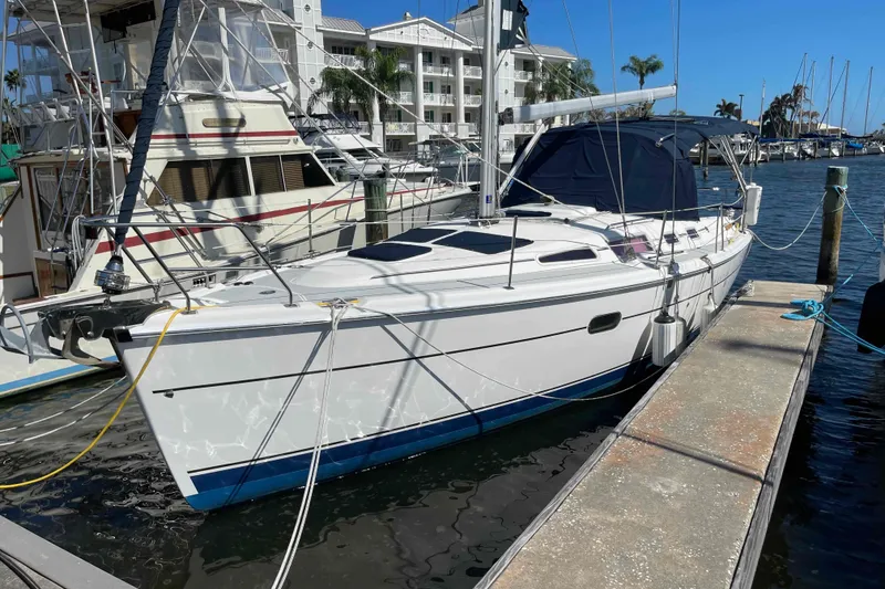 The Image of 2006 Hunter 36 sailboat docked at marina, sunny day, waterfront buildings in background. - 0