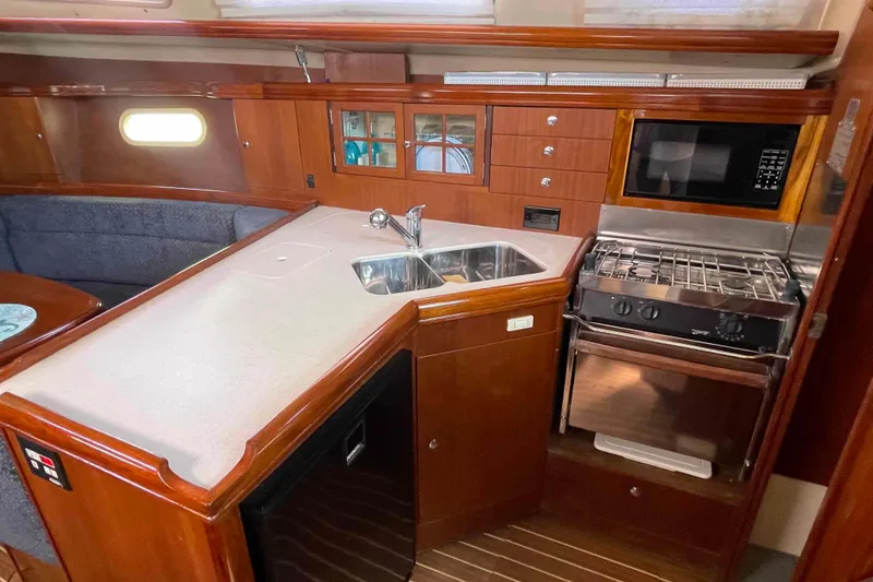 Slide: The Image of 2006 Hunter 36 yacht interior kitchen with wood cabinetry, sink, stove, and microwave. - 3