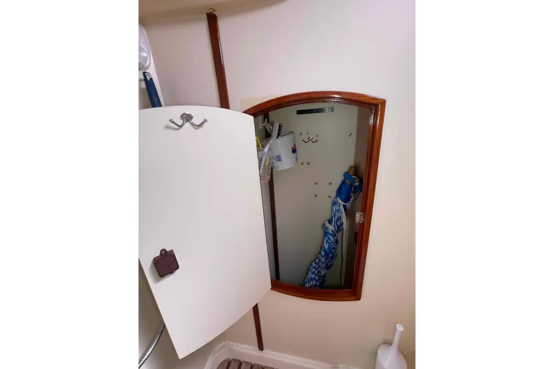 Slide: The Image of Open storage cabinet inside 2006 Hunter 36 boat, featuring cleaning supplies and nautical decor. - 31