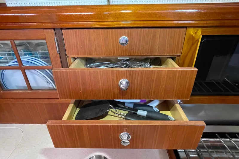 Slide: The Image of Wooden kitchen drawers in a 2006 Hunter 36 yacht, containing utensils and cutlery. - 34