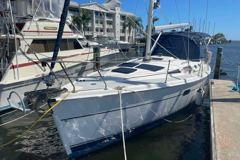Slide: The Image of 2006 Hunter 36 sailboat docked at marina, surrounded by other boats and waterfront buildings. - 50