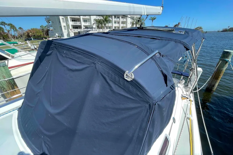 Slide: The Image of 2006 Hunter 36 sailboat with blue canvas cover docked by the water. - 58