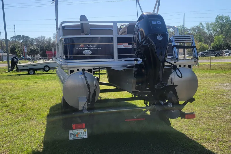 Slide: The Image of 2023 Sun Tracker Bass Buggy 18 DLX pontoon boat with Mercury 60 HP engine, parked on grass. - 4