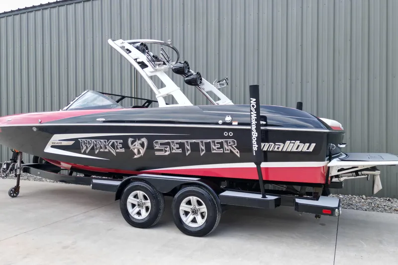 Slide: The Image of 2012 Malibu Wakesetter 22 MXZ boat on trailer, black and red design. - 10