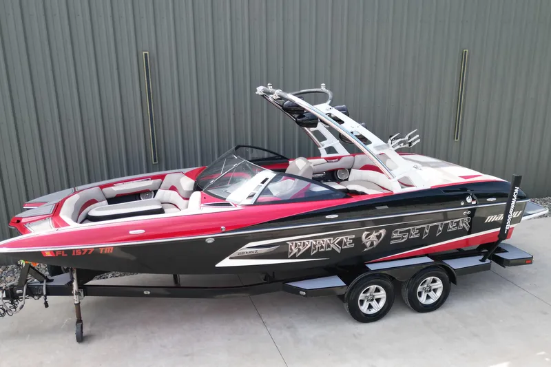 Slide: The Image of 2012 Malibu Wakesetter 22 MXZ boat with red and black design on a trailer. - 2