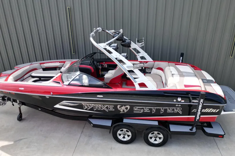 Slide: The Image of 2012 Malibu Wakesetter 22 MXZ boat with red and black design on trailer. - 3