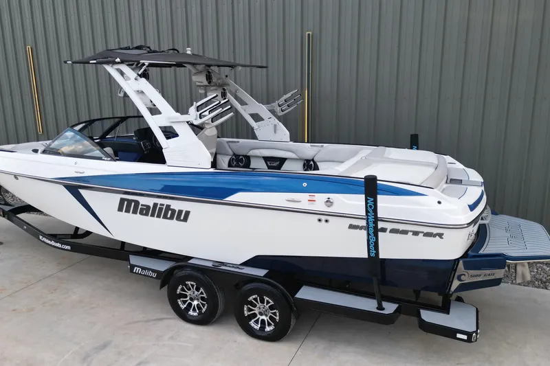 Slide: The Image of 2017 Malibu Wakesetter 25 LSV boat on trailer, side view, blue and white design. - 2