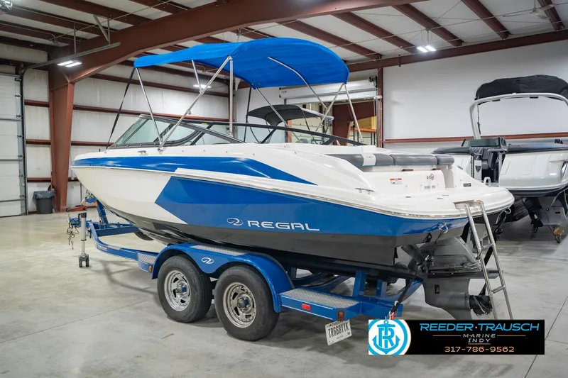 Slide: The Image of 2015 Regal 2000 ESX Bowrider boat with blue accents on a trailer in a showroom. - 10