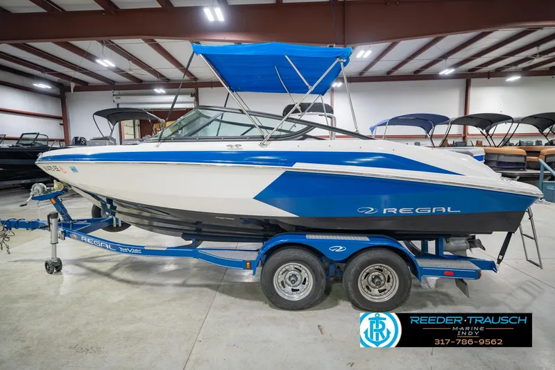 Slide: The Image of 2015 Regal 2000 ESX Bowrider boat in showroom, blue and white design, on trailer. - 11