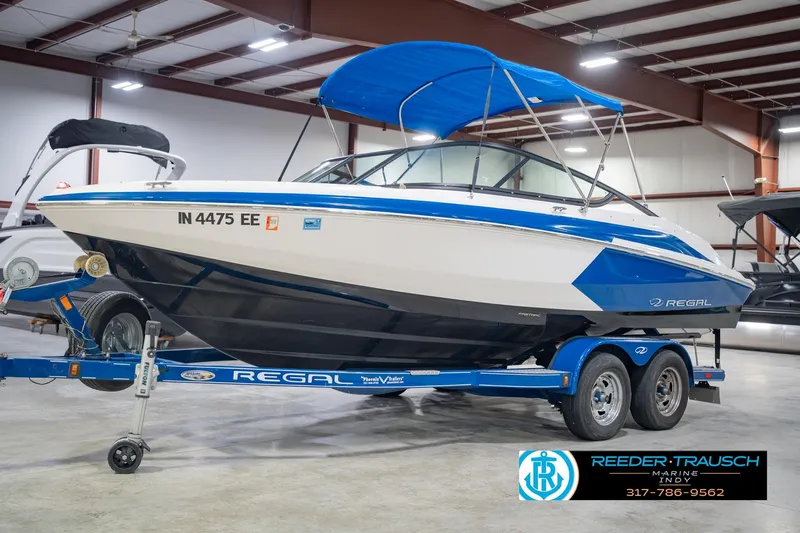 Slide: The Image of 2015 Regal 2000 ESX Bowrider boat with blue canopy on trailer in showroom. - 4