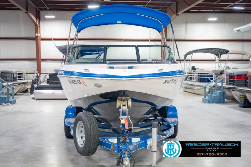 Slide: The Image of 2015 Regal 2000 ESX Bowrider with blue canopy on trailer in showroom. - 5