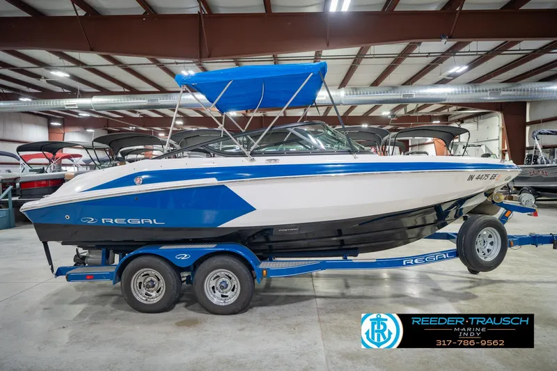 Slide: The Image of 2015 Regal 2000 ESX Bowrider boat with blue accents on a trailer in a showroom. - 7
