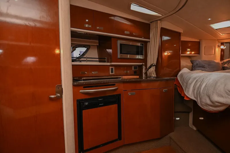 Slide: The Image of 2012 Sea Ray Sundancer 330 interior kitchen with wood cabinetry and compact appliances. - 35
