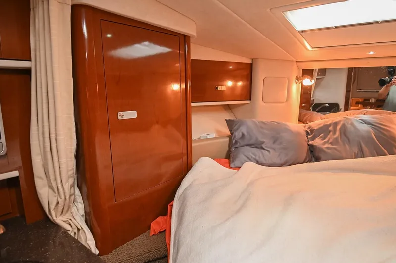 Slide: The Image of 2012 Sea Ray Sundancer 330 cabin interior with wooden cabinets and cozy bedding. - 42