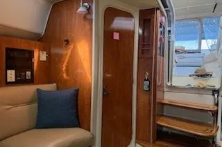 Slide: The Image of Interior of a 2003 Doral 310se boat, featuring wood paneling and cozy seating. - 8