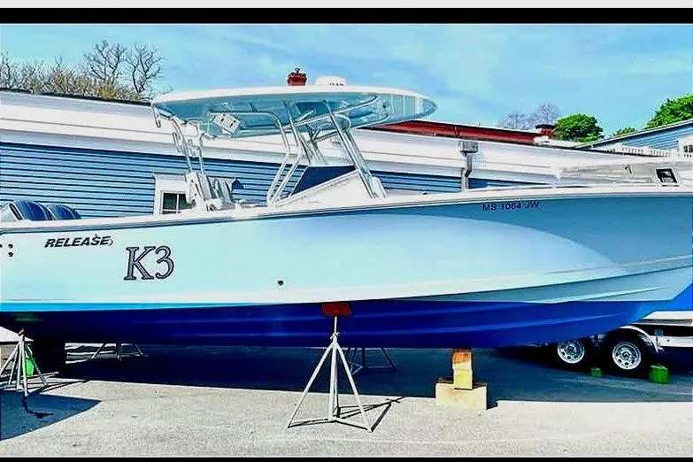 Slide: The Image of 2020 Release 301 RX boat on stands, blue and white hull, outdoor setting. - 4