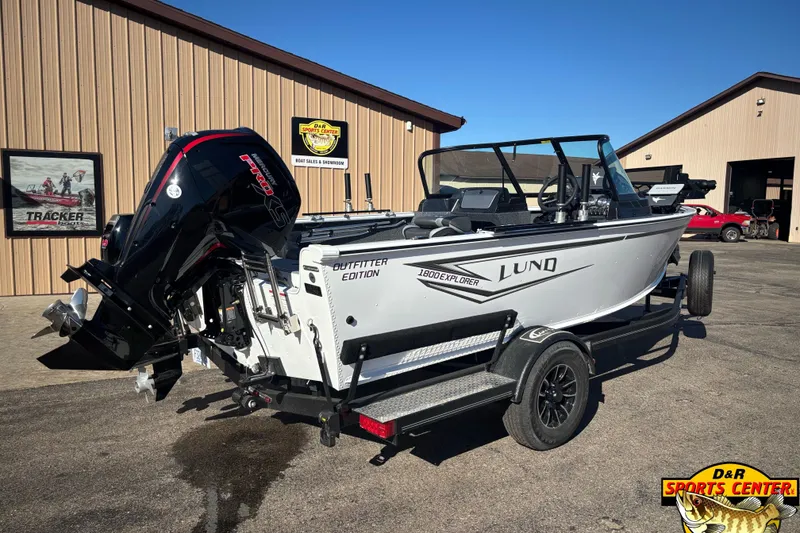 Slide: The Image of 2026 Lund 1800 Explorer Sport boat on trailer at dealership, featuring powerful outboard motor. - 1