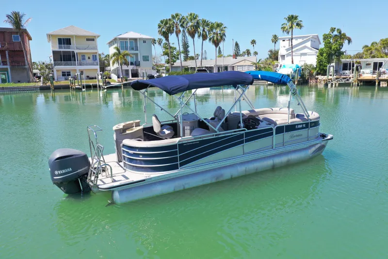 Slide: The Image of 2015 Berkshire 250E Premium pontoon boat on calm water, surrounded by waterfront homes. - 1