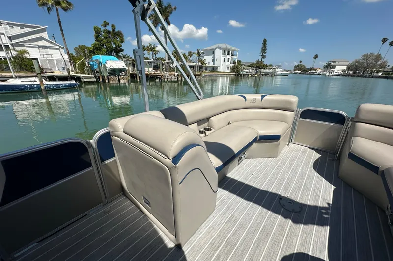 Slide: The Image of 2015 Berkshire 250E Premium pontoon boat with beige seating, docked by waterfront homes. - 10