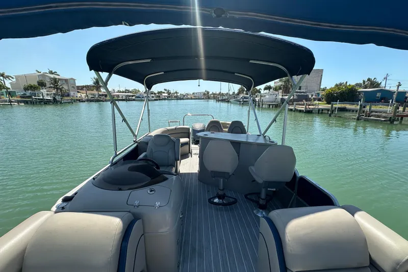 Slide: The Image of 2015 Berkshire 250E Premium pontoon boat on calm water, featuring spacious seating and canopy. - 12