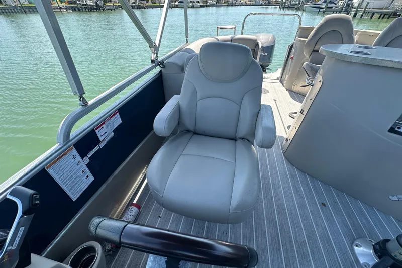 Slide: The Image of 2015 Berkshire 250E Premium boat interior with captain's chair and helm, docked on calm water. - 14