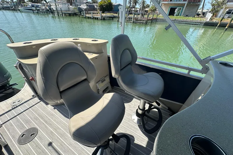 Slide: The Image of 2015 Berkshire 250E Premium boat interior with swivel seats, overlooking a serene marina. - 19