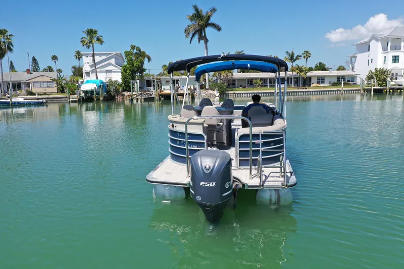 Slide: The Image of 2015 Berkshire 250E Premium pontoon boat on serene waterway with palm trees. - 2