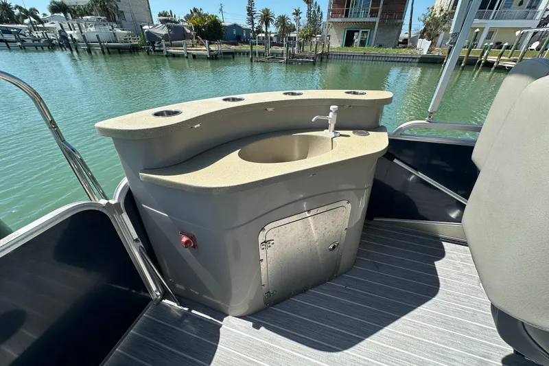 Slide: The Image of 2015 Berkshire 250E Premium boat with onboard sink and storage, docked by waterfront homes. - 23