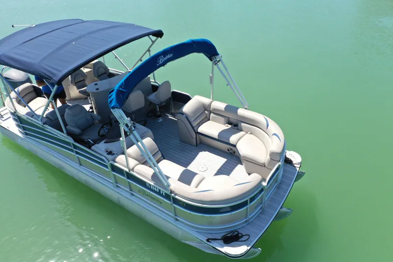Slide: The Image of 2015 Berkshire 250E Premium pontoon boat on calm green water, featuring spacious seating and canopy. - 4