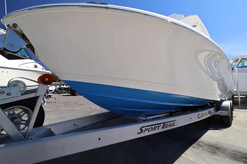 Slide: The Image of 2026 Caymas 291 boat on Sport Trail trailer, showcasing sleek design and blue hull. - 11