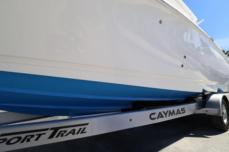 Slide: The Image of 2026 Caymas 291 boat on trailer, showcasing sleek white and blue hull design. - 8