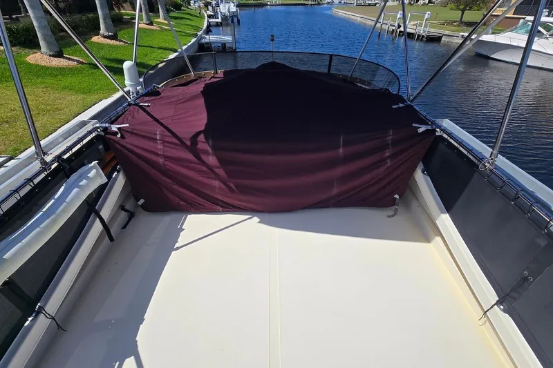 Slide: The Image of 2005 Camano 31 Troll boat deck with maroon cover, docked by a canal. - 11
