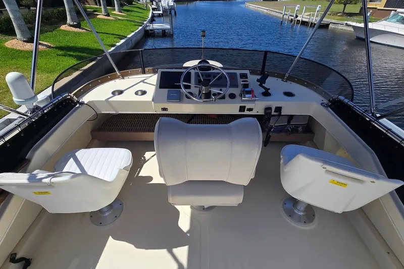 Slide: The Image of 2005 Camano 31 Troll boat cockpit with steering wheel and seating, docked by a canal. - 12