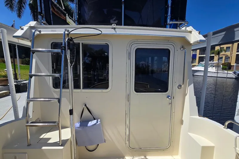 Slide: The Image of 2005 Camano 31 Troll boat stern with ladder and door, docked in marina. - 17