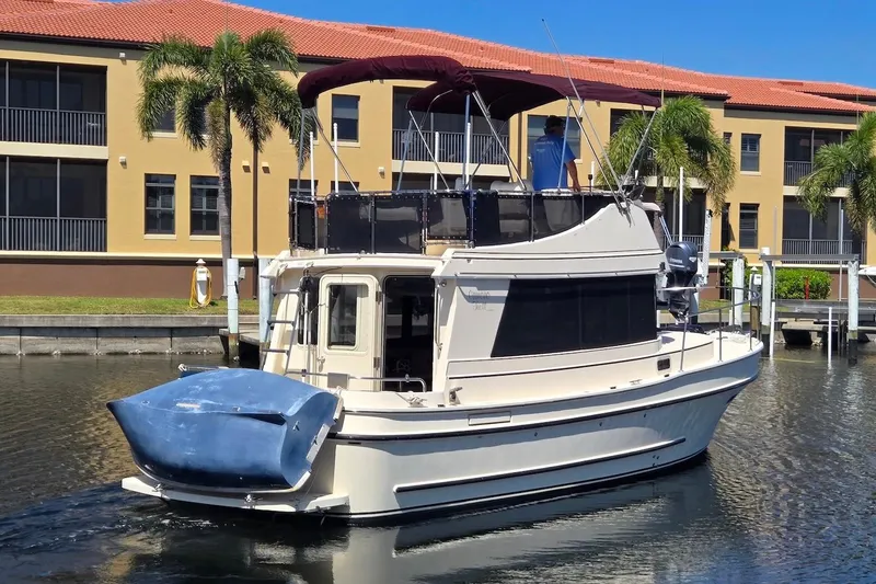 Slide: The Image of 2005 Camano 31 Troll boat docked near waterfront buildings with palm trees. - 2