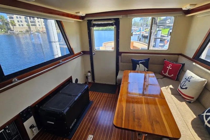Slide: The Image of Interior of 2005 Camano 31 Troll boat with wooden table, nautical-themed cushions, and large windows. - 21