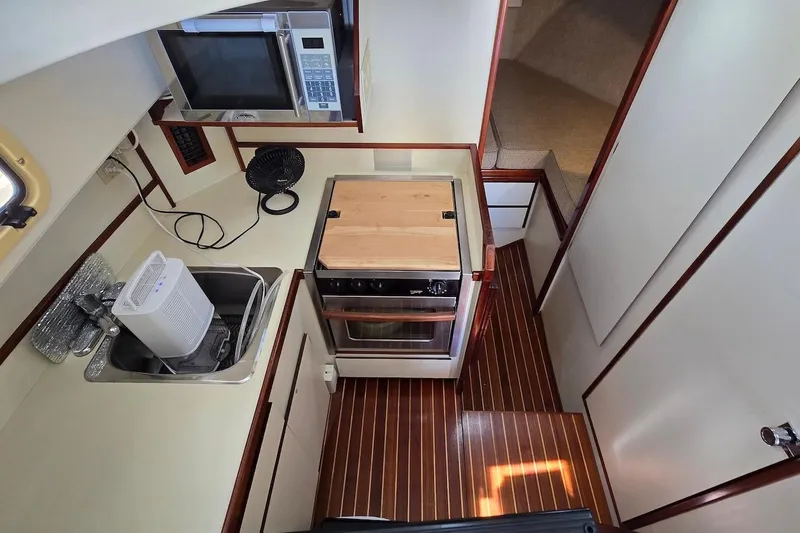 Slide: The Image of 2005 Camano 31 Troll galley with stove, microwave, and sink on wooden flooring. - 24