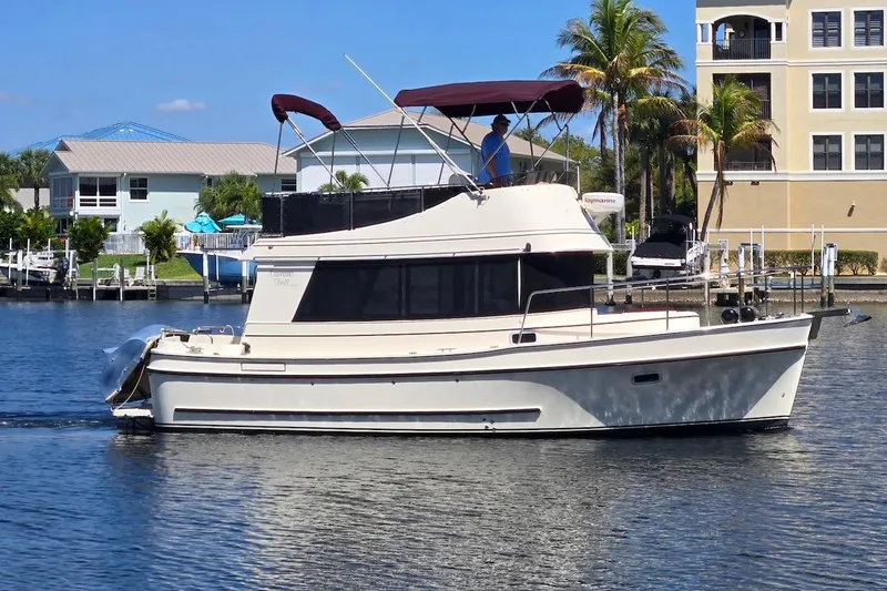 Slide: The Image of 2005 Camano 31 Troll boat cruising on a sunny waterfront with palm trees. - 3