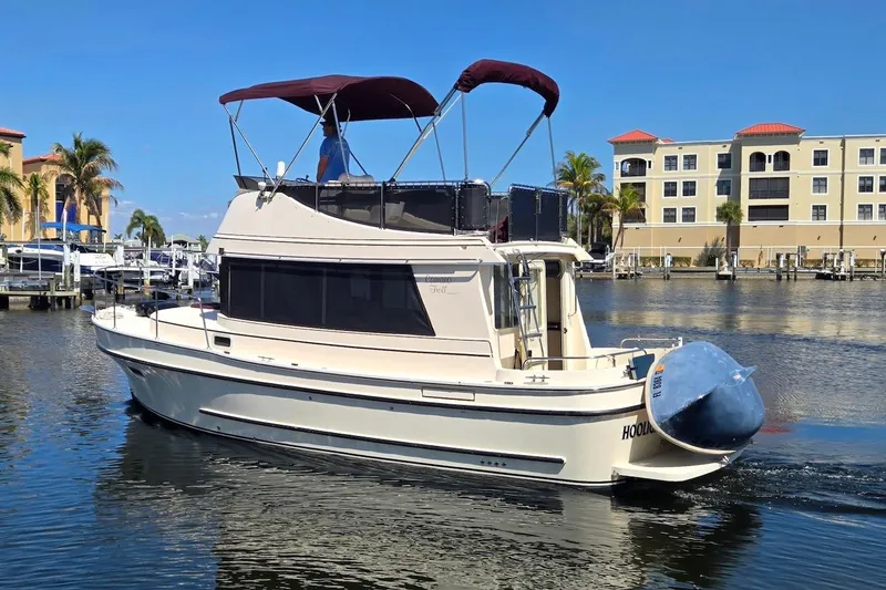 Slide: The Image of 2005 Camano 31 Troll boat cruising in a marina with palm trees and buildings. - 6