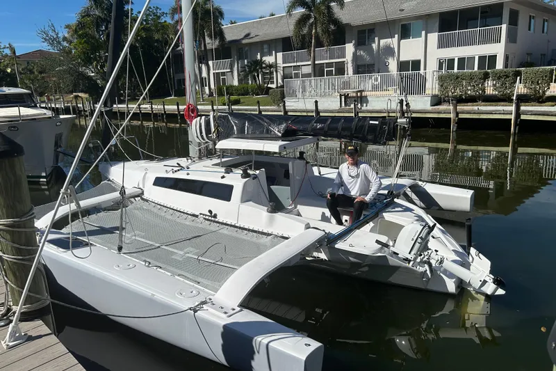 The Image of 2025 Corsair 760 trimaran docked in a marina with a person onboard. - 1