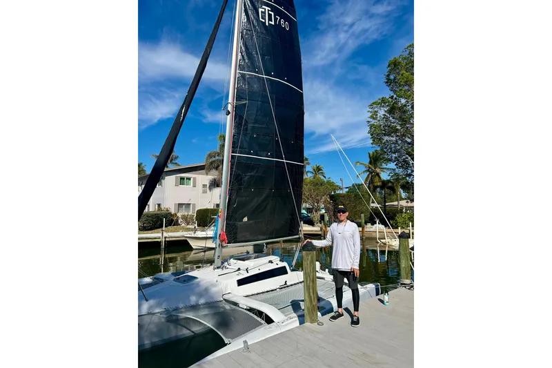 Slide: The Image of Man standing beside 2025 Corsair 760 sailboat at a sunny marina. - 4