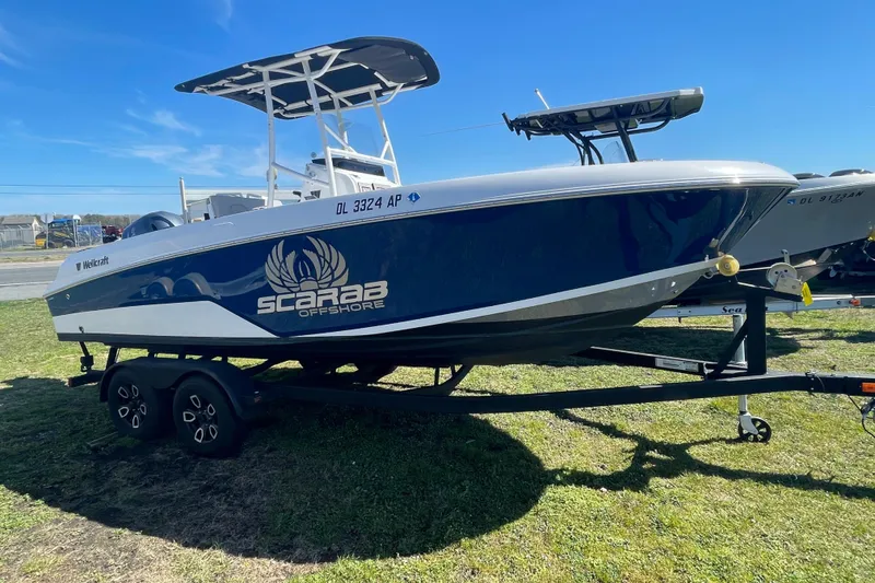 Slide: The Image of 2022 Wellcraft 202 Fisherman boat on trailer, blue and white design, Scarab Offshore branding. - 12